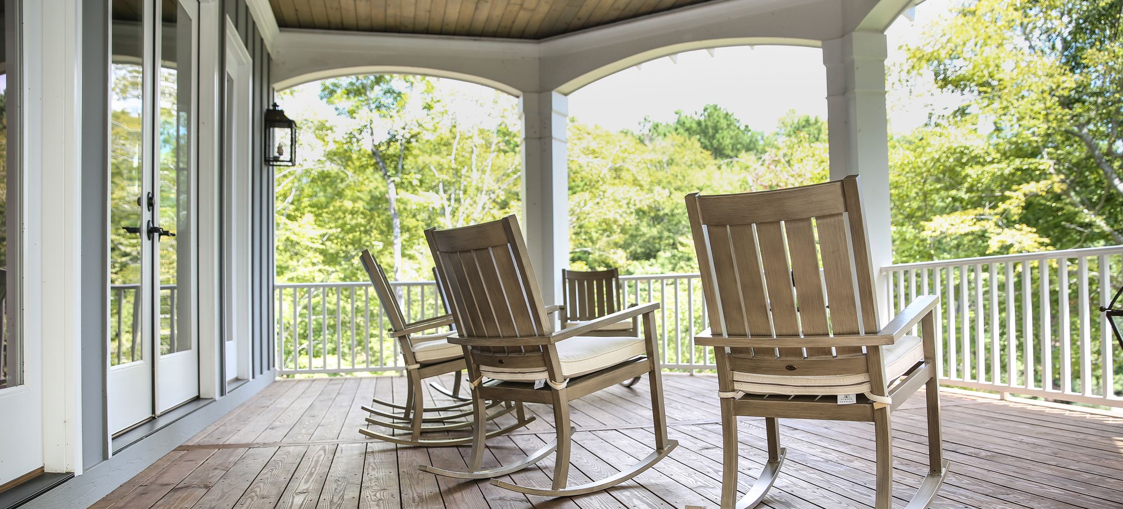 Rocking chairs on a covered Southern porch looking out to summer trees